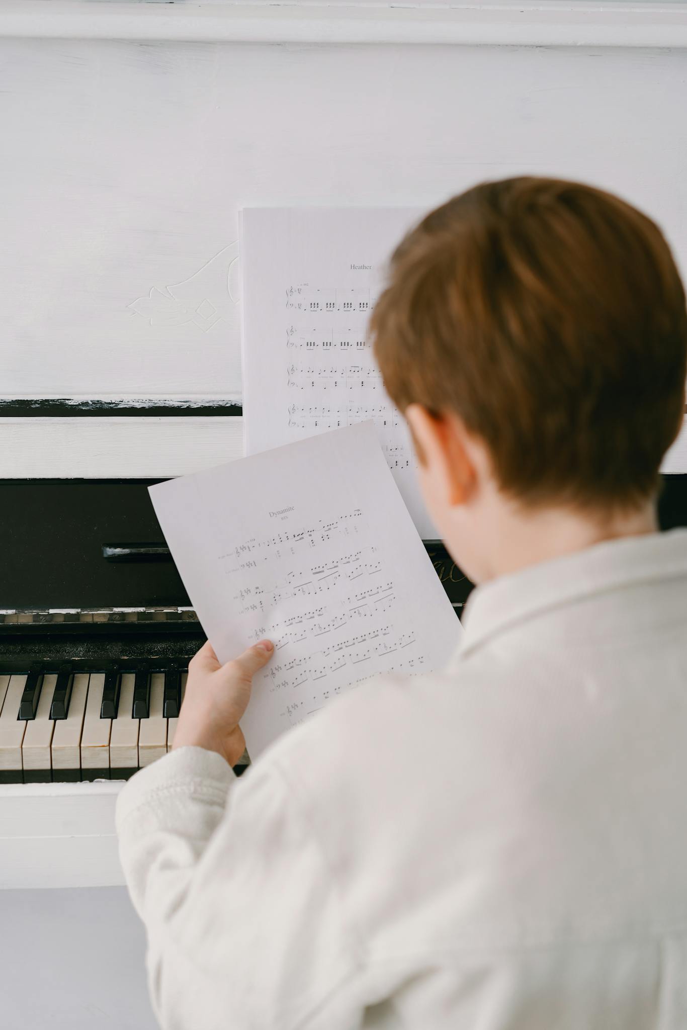 A child focused on reading sheet music at a piano, emphasizing musical learning.