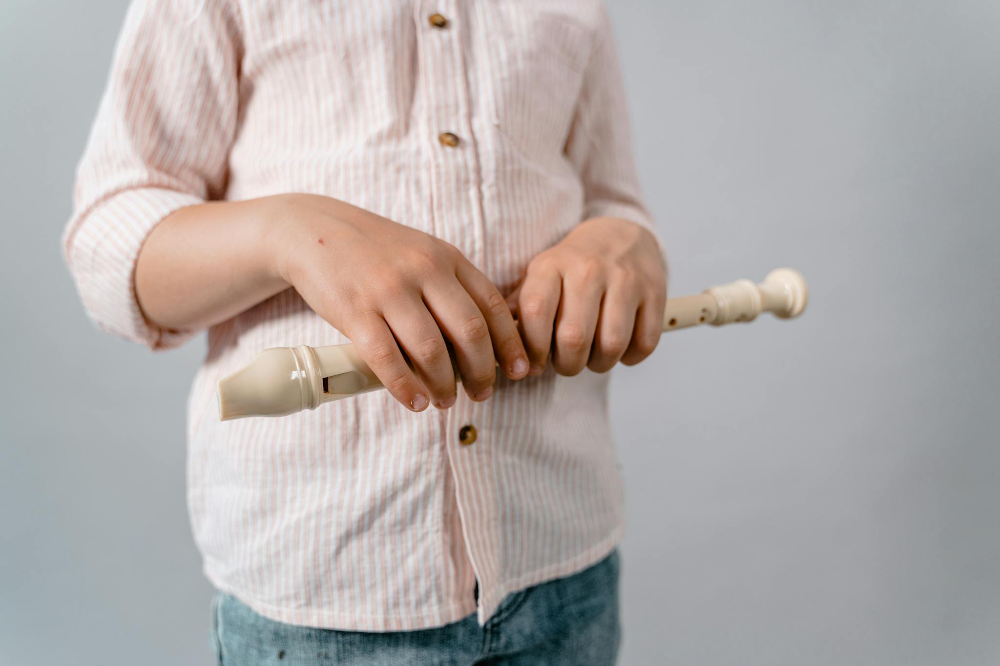 Close-up of a child's hands holding a recorder, focusing on music education.