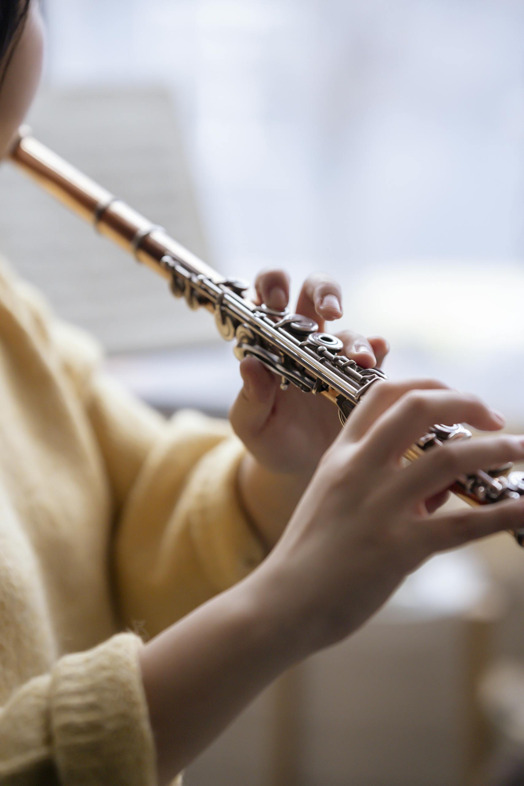 Close-up of a woman playing the flute indoors with a serene focus on the instrument and hands.