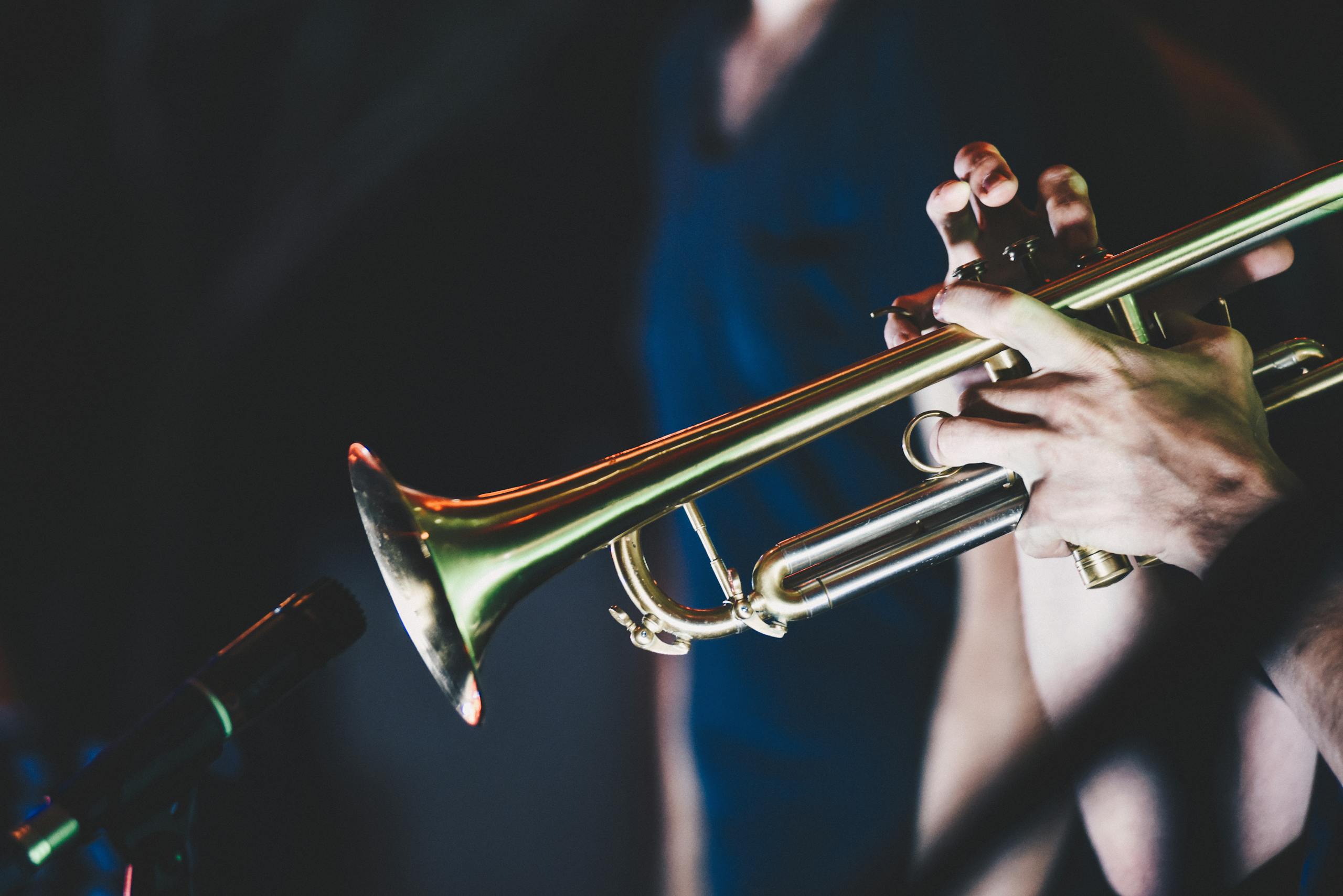 Close-up shot of a musician playing the trumpet during a live performance, highlighting musical passion.